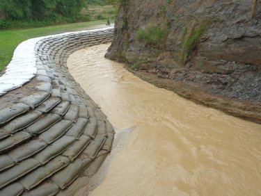 Die Kanäle werden mit Sandsäcken stabilisiert, um die Felder der bangladeschischen Kleinbauernfamilien zu schützen.