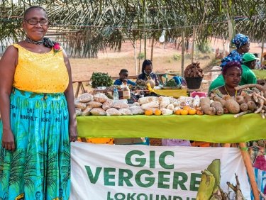 Frau lacht und bietet eigene Ernte auf lokalem Markt an