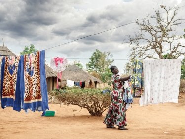 Frau in einem Dorf in Uganda hängt Wäsche auf